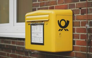 yellow mailbox on brown wall bricks