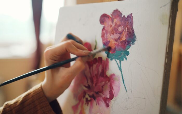 An artist paints flowers on a canvas.