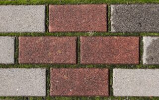 a close up of a brick sidewalk with grass growing on it